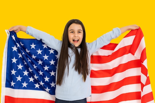 szczęśliwe dziecko dziewczynka z flagą Stanów Zjednoczonych Ameryki USA na żółtym tle koloru.