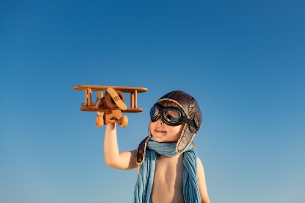 Szczęśliwe Dziecko Grając Z Rocznika Drewniany Samolot. Dziecko, Zabawy Na świeżym Powietrzu Na Tle Nieba Latem