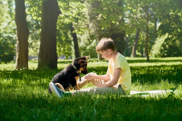 Szczęśliwe dziecko i mały szczeniak bawią się razem w parku miejskim