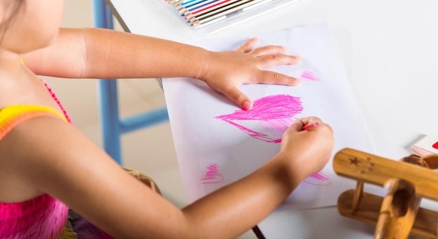 Zdjęcie szczęśliwe dziecko mała dziewczynka kolorowy rysunek różowe serce na białym papierze