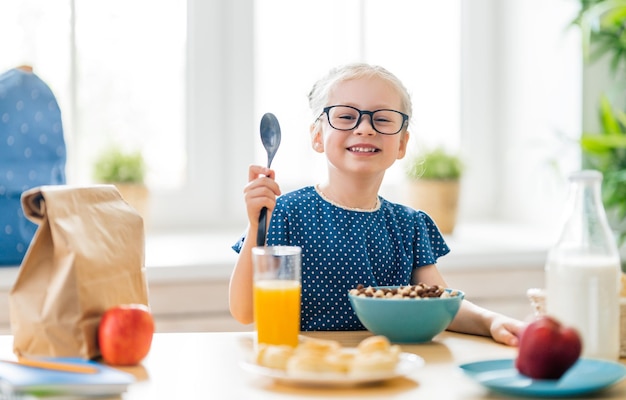 Szczęśliwe dziecko o śniadanie. Dziecko jedzenie płatków w kuchni.