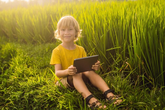 Szczęśliwe Dziecko Siedzi Na Polu Trzymając Tablet Chłopiec Siedzi Na Trawie W Słoneczny Dzień Domowa Nauka Lub Gra Na Tablecie