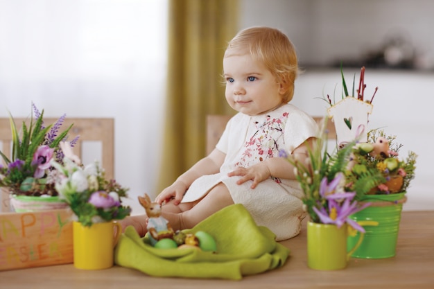 Zdjęcie szczęśliwe dziecko siedzi przy stole i trzymając jajko wielkanocne