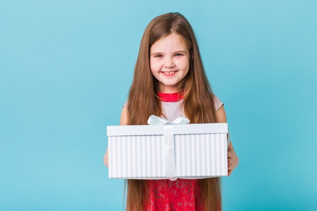 Szczęśliwe dziecko trzyma prezenty urodzinowe na niebieskiej ścianie.