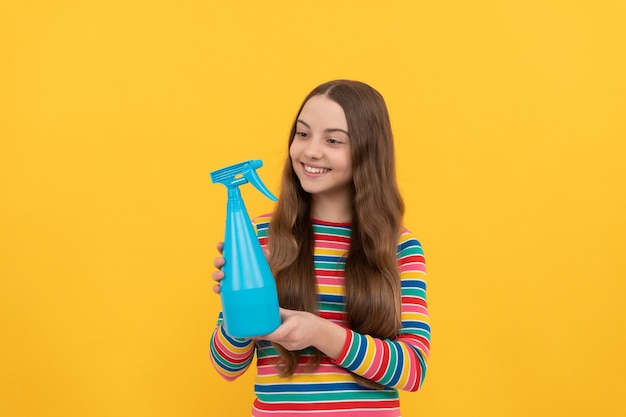 Szczęśliwe dziecko trzymaj dezynfekującą butelkę do rozpylania na żółtym tle kopii przestrzeni, spray.