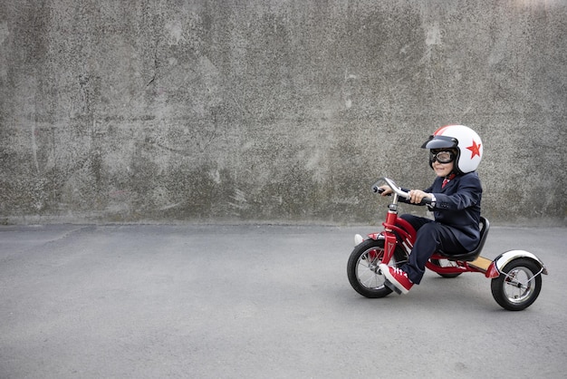 Szczęśliwe dziecko udaje biznesmena Śmieszne dziecko jeździ na rowerze na świeżym powietrzu Powrót do pracy i koncepcji pomysłu na biznes