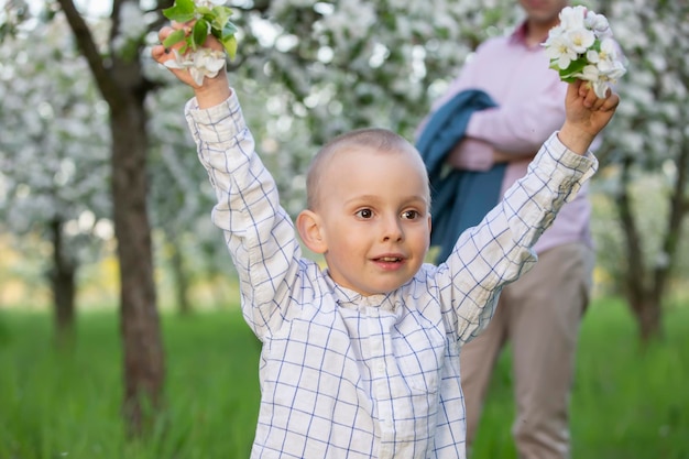 Szczęśliwe dziecko w kwitnącym wiosennym ogrodzie raduje się uśmiechami