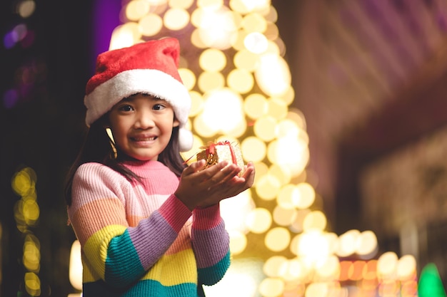 Szczęśliwe dziecko w Santa czerwony kapelusz trzymając prezenty świąteczne. Czas świąt.