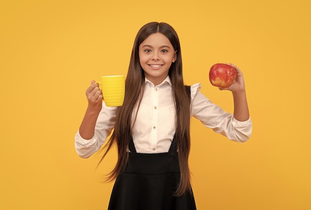 Szczęśliwe dziecko w szkole w mundurze trzyma zdrowie jabłka i butelki z wodą