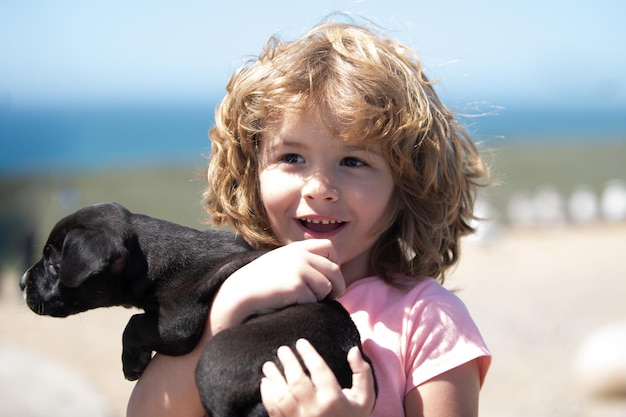 Szczęśliwe dziecko ze szczeniakiem pies portret dzieci chłopiec ze zwierzakiem bawiące się poza beztroskim dzieciństwem