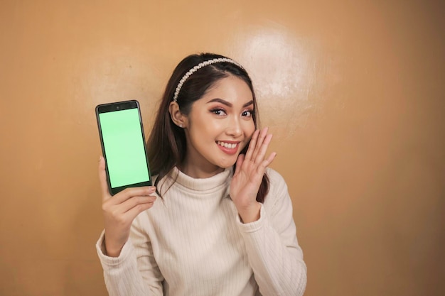 Szczęśliwe i uśmiechnięte młode Azjatki pokazujące zielony pusty ekran