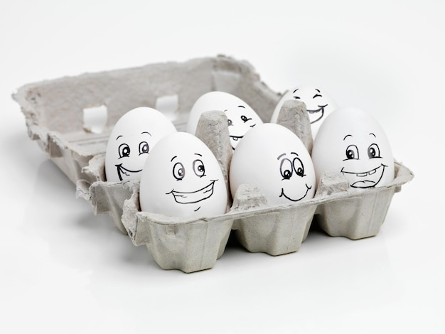 Szczęśliwe jajka tworzą zdrową żywność. Studio ujęcie twarzy narysowanych na kartonie z jajkami