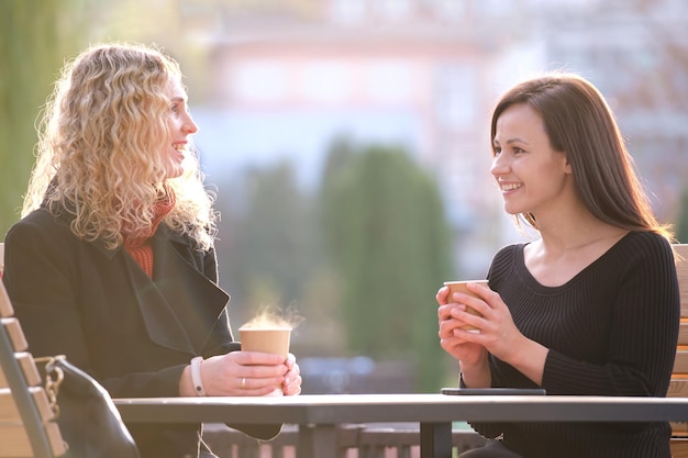 Szczęśliwe kobiety biznesu rozmawiają podczas spotkania na przerwę na kawę w miejskiej kawiarni ulicznej. Koncepcja przyjaźni między partnerami biznesowymi.