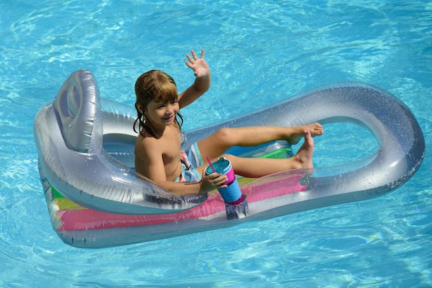 Szczęśliwe letnie wakacje dziecko w basenie chłopiec pływający na basenie zabawny dzieciak na nadmuchiwanym gumowym macie