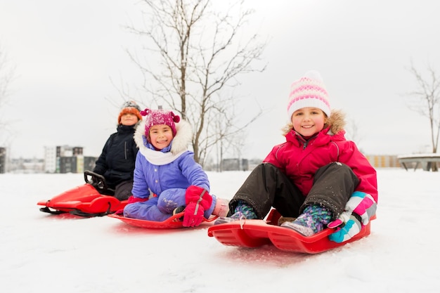 Zdjęcie szczęśliwe małe dzieci ślizgające się na saniach zimą
