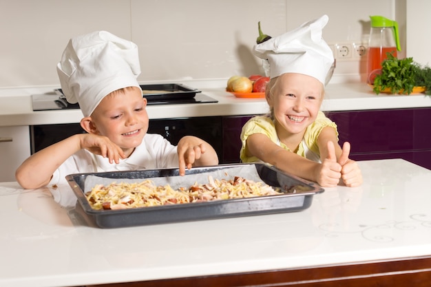 Szczęśliwe małe dzieci z powodzeniem zrobiły pizzę w kuchni