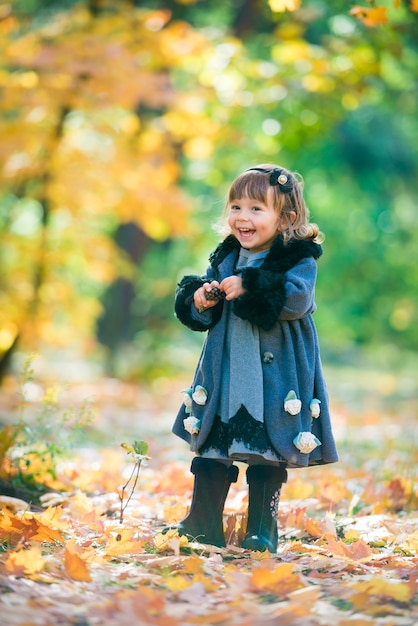Szczęśliwe małe dziecko, dziewczynka śmiejąc się i grając jesienią na spacer natury na świeżym powietrzu.