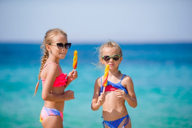 Szczęśliwe małe dziewczynki je lody podczas wakacji na plaży