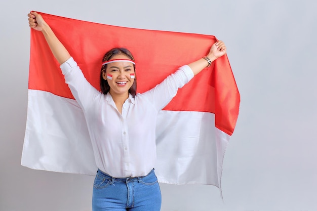 Szczęśliwe młode Azjatki świętują dzień niepodległości Indonezji trzymając indonezyjską flagę na białym tle