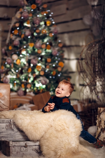 Szczęśliwe młode dziecko w pobliżu choinki z prezentami i mandarynek
