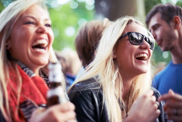 Zdjęcie szczęśliwe napoje i kobiety na koncercie festiwalu muzycznego lub imprezie śmieją się podekscytowani i cieszą się zewnętrznym rave lub techno świętowanie młodzi przyjaciele publiczność lub tłum z butelką piwa lub alkoholem na wakacje