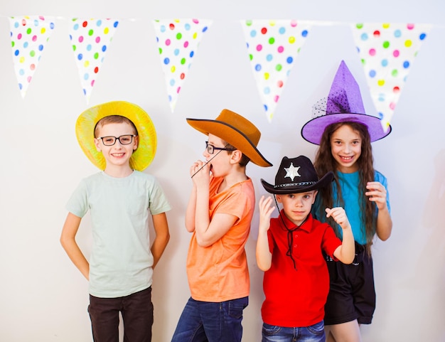 Szczęśliwe podekscytowane dzieci bawiące się razem na przyjęciu urodzinowym Dzieci w śmiesznych czapkach i kostiumach Rozrywka i wypoczynek dla dzieci