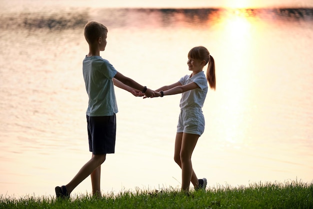 Szczęśliwe rodzeństwo stojące razem trzymające się za ręce w letnim parku Brat i siostra małych dzieci relaksujący się na świeżym powietrzu Koncepcja rodzinnej miłości i związku