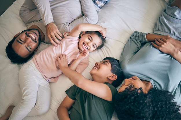 Szczęśliwe rodzinne łóżko i zabawa podczas weekendu lub dnia wolnego podczas wspólnego relaksu nad domem Widok z góry na ojca, matkę i dzieci uśmiechających się z radości lub śmiejących się dla zabawy rodziców lub poranek w sypialni