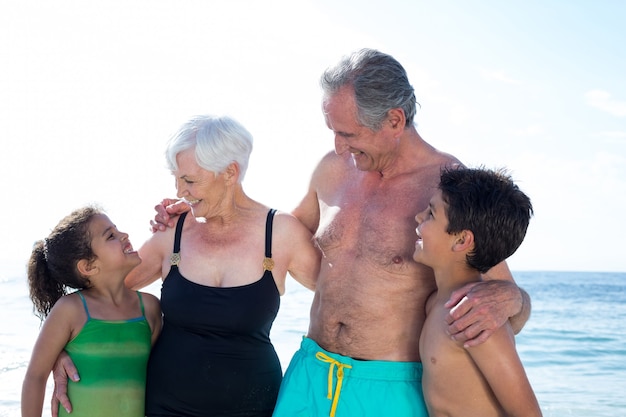 Szczęśliwe wnuki i dziadkowie stojąc na plaży
