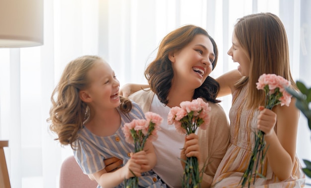 Szczęśliwego dnia Córki dzieci gratulują mamie i dają jej kwiaty Mama i dziewczynki uśmiechają się