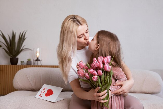 Szczęśliwego Dnia Matki Córka dziecka gratuluje matce i wręcza jej kwiaty kartkę Mamo