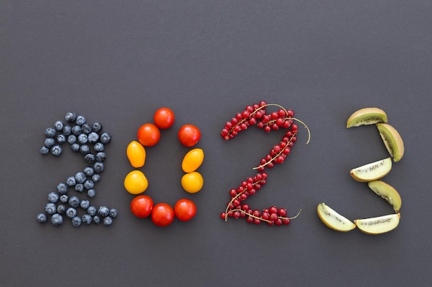 Zdjęcie szczęśliwego nowego roku 2023 numer z owoców i jagód na czarno