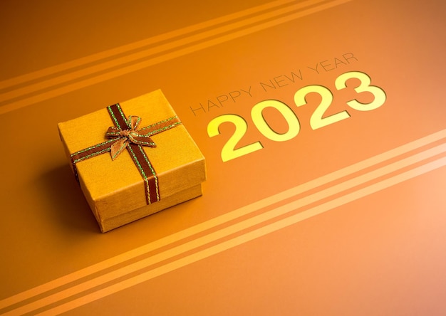 Szczęśliwego Nowego Roku 2023 tło 2023 rok numery z małym złotym prezentem prezentowym ze wstążką na złotym tle w minimalistycznym stylu