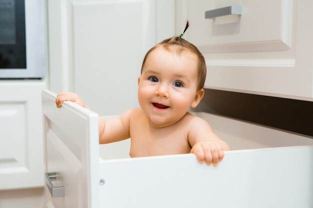 Szczęśliwej dziewczynki uśmiechnięty obsiadanie w kuchennej szufladzie z nieckami