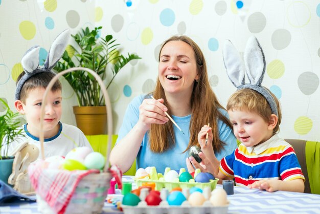 Zdjęcie szczęśliwej wielkanocy matka i jej dzieci malują jaja wielkanocne