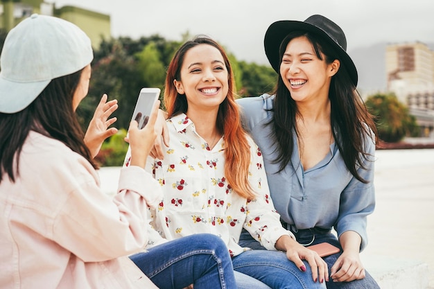 Zdjęcie szczęśliwi azjaci dobrze się bawią przy użyciu telefonu komórkowego na zewnątrz. skup się na środkowej twarzy dziewczyny