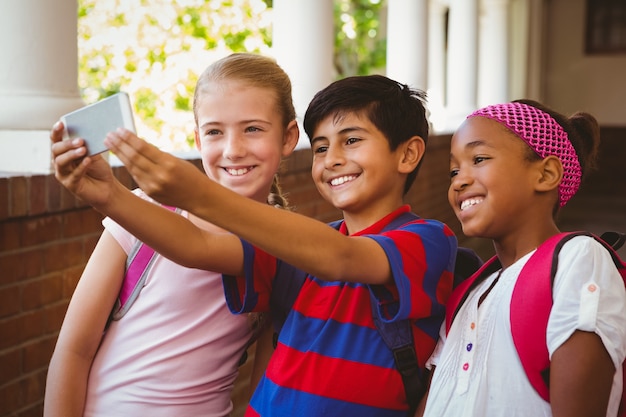 Szczęśliwi dzieciaki bierze selfie w szkolnym korytarzu