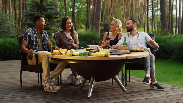 Szczęśliwi faceci spędzający weekend w letnim lesie Koledzy relaksujący się przy grillu?