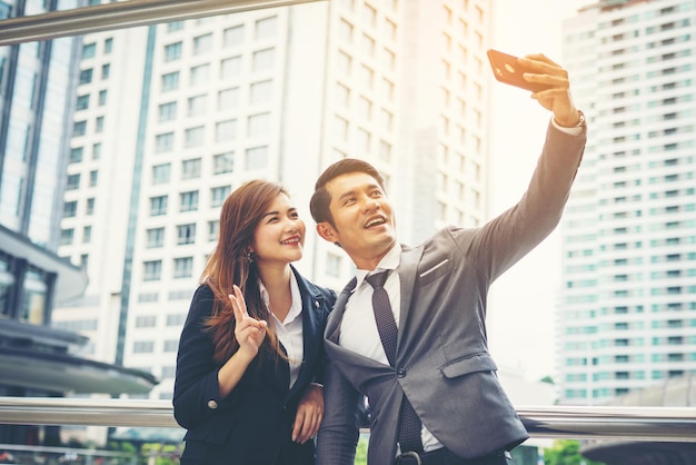 Szczęśliwi koledzy robią sobie selfie, stojąc przy budynkach w mieście.