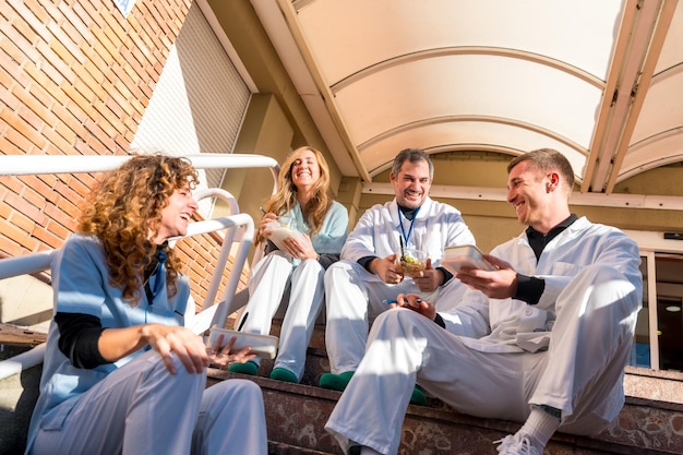 Zdjęcie szczęśliwi lekarze i pielęgniarki dzielą się obiadem przed szpitalem