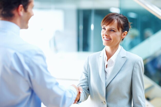 Zdjęcie szczęśliwi ludzie biznesu ściskają ręce i spotykają się na partnerstwo b2b lub umowę korporacyjną w biurze biznesmen i kobieta ściskają ręce na powitanie, wprowadzenie lub umowę firmową razem w miejscu pracy