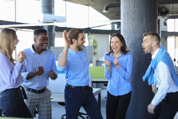 Szczęśliwi ludzie biznesu śmieją się w biurze. Odnoszący sukcesy współpracownicy w zespole żartują i bawią się razem w pracy.