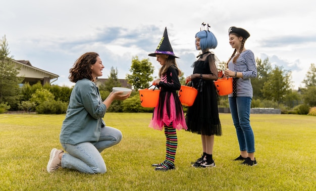 Szczęśliwi ludzie świętują Halloween Dorośli traktują dzieci słodyczami na zewnątrz