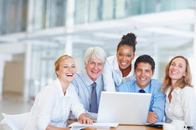 Szczęśliwi menedżerowie korzystający z laptopa Portret szczęśliwych ludzi biznesu pracujących razem na laptopie