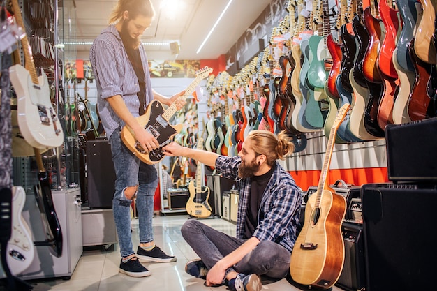 Szczęśliwi młodzi chłopcy skoncentrowani na jednej gitarze elektrycznej