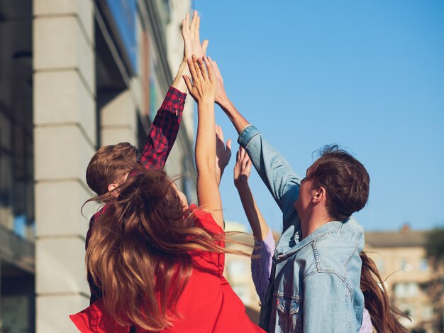 Zdjęcie szczęśliwi młodzi przyjaciele pracy zespołowej. grupa mężczyzny i kobiety z rękami razem robi piątkę gestów