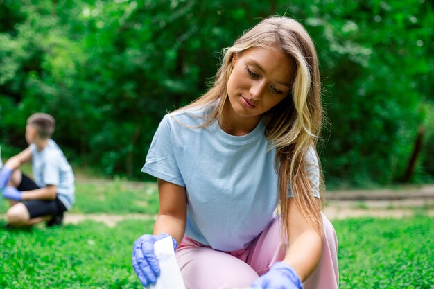 Szczęśliwi pracownicy społeczności sprzątający lokalny park Mają worek na śmieci i napełniają je śmieciami, które znaleźli w parku?