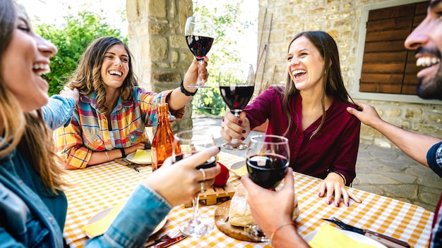 Zdjęcie szczęśliwi przyjaciele bawiący się opiekaniem czerwonego wina na imprezie na tarasie wiejskiego domu