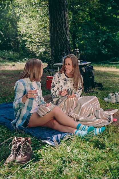 Szczęśliwi Przyjaciele Młodych Kobiet śmieją Się Siedząc Na Kempingu W Lesie
