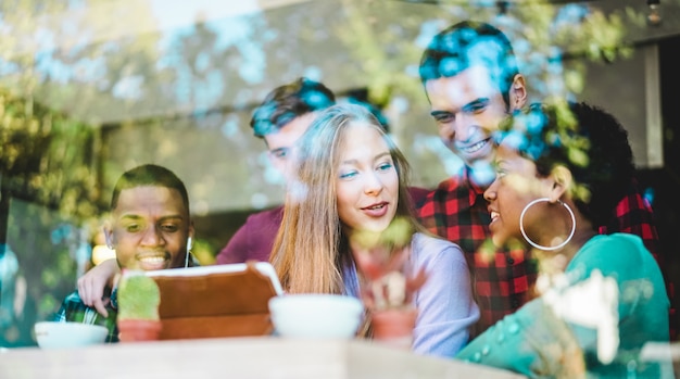 Szczęśliwi przyjaciele ogląda wideo na pastylka komputerze wśrodku coworking interneta baru. Młodzi ludzie w wieku milenijnym bawią się z trendami technologicznymi w cyber cafe